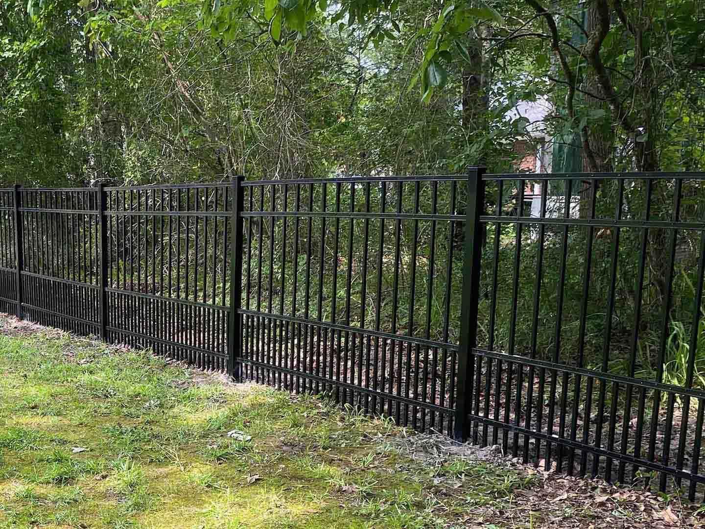 Black aluminum ornamental fence with ball-top pickets along a grassy yard