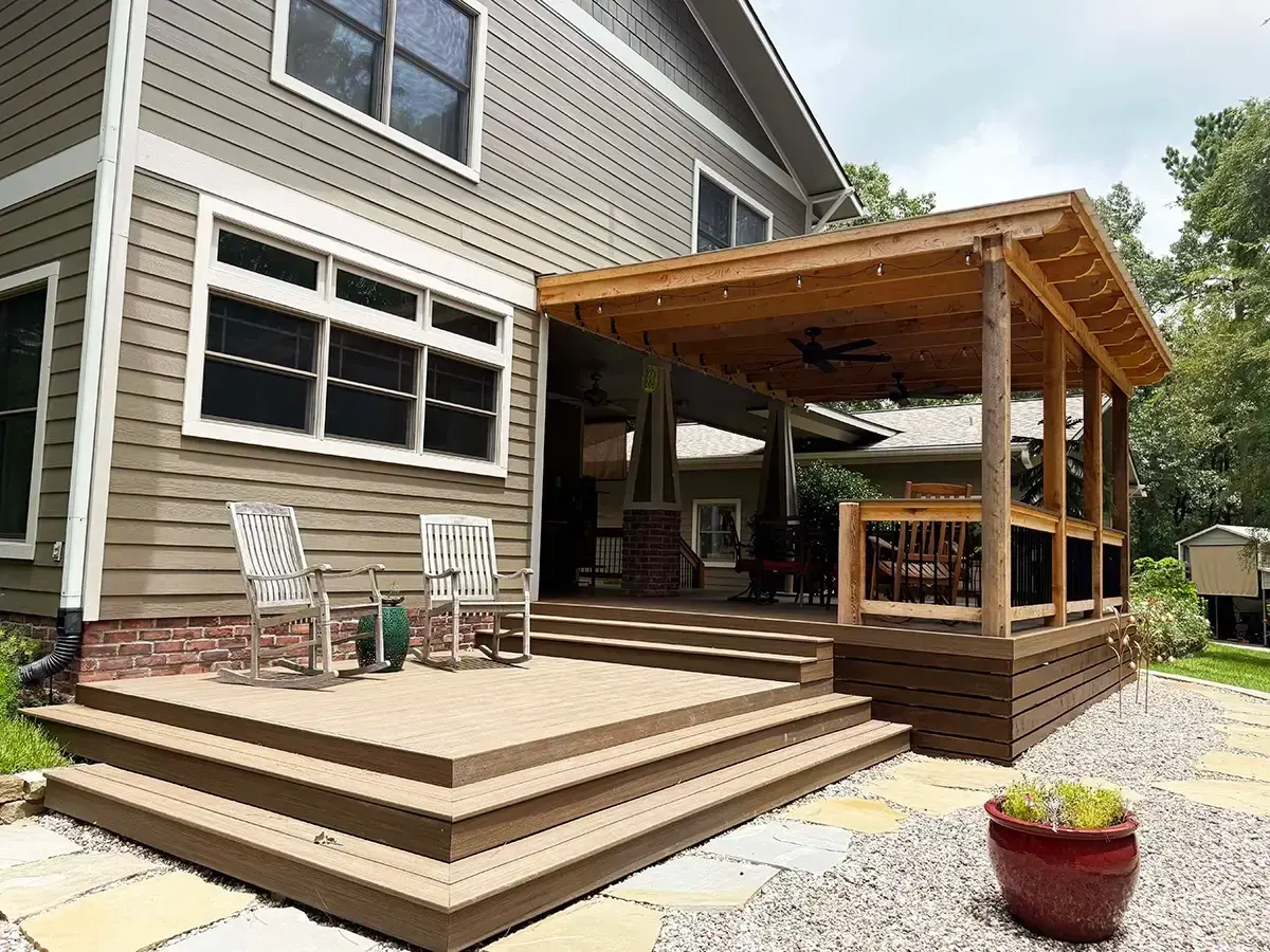 Wood deck with a covered pergola and ceiling fan attached to a residential home