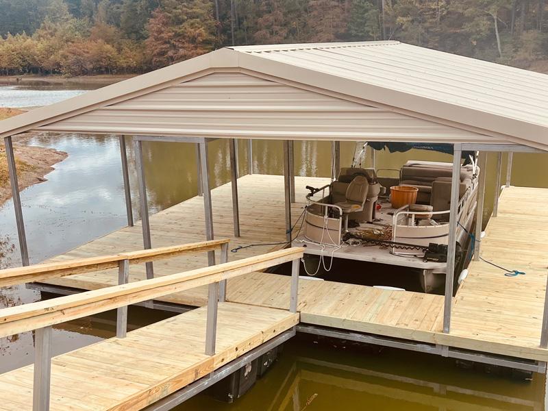 Wood and metal boathouse over a lake with covered pontoon boat slip