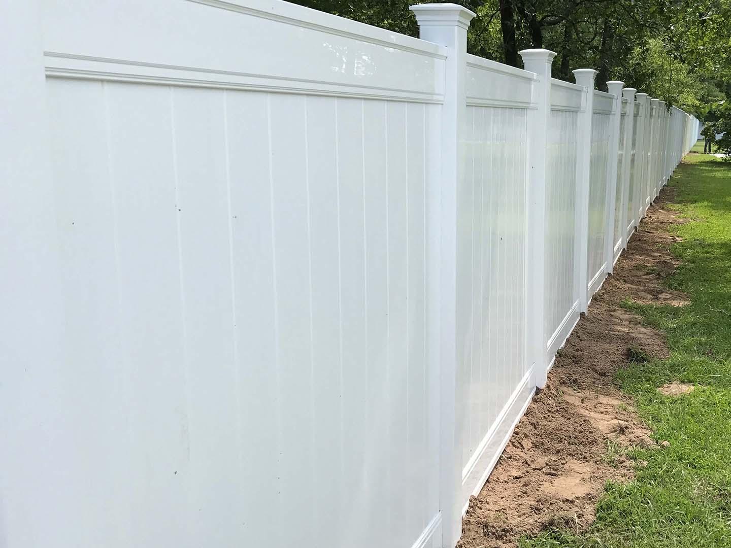 White vinyl privacy fence with new england post caps along a rural property
